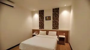 A hotel room with a large bed, a bedside table, a nightstand, and a wall-mounted telephone. - Hotel 88 Banjarmasin (Banjarmasin)