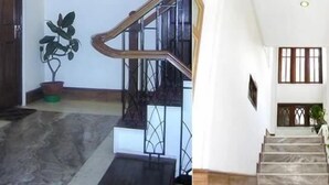 A staircase with a handrail, a potted plant, and a window with bars. - Hotel Shangri-la Regency (Darjeeling)