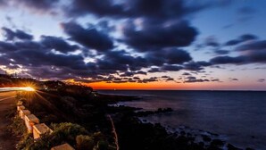 Une vue sur le coucher de soleil sur la côte, avec une route menant à un rivage rocheux.