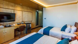 Une chambre d’hôtel avec deux lits, un bureau, une télévision et une kitchenette.