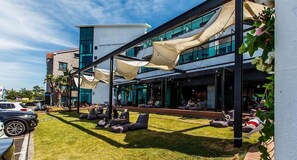 An outdoor seating area with modern furniture and a building with large windows in the background. - Aewol Cutiepie Hotel (Jeju City)