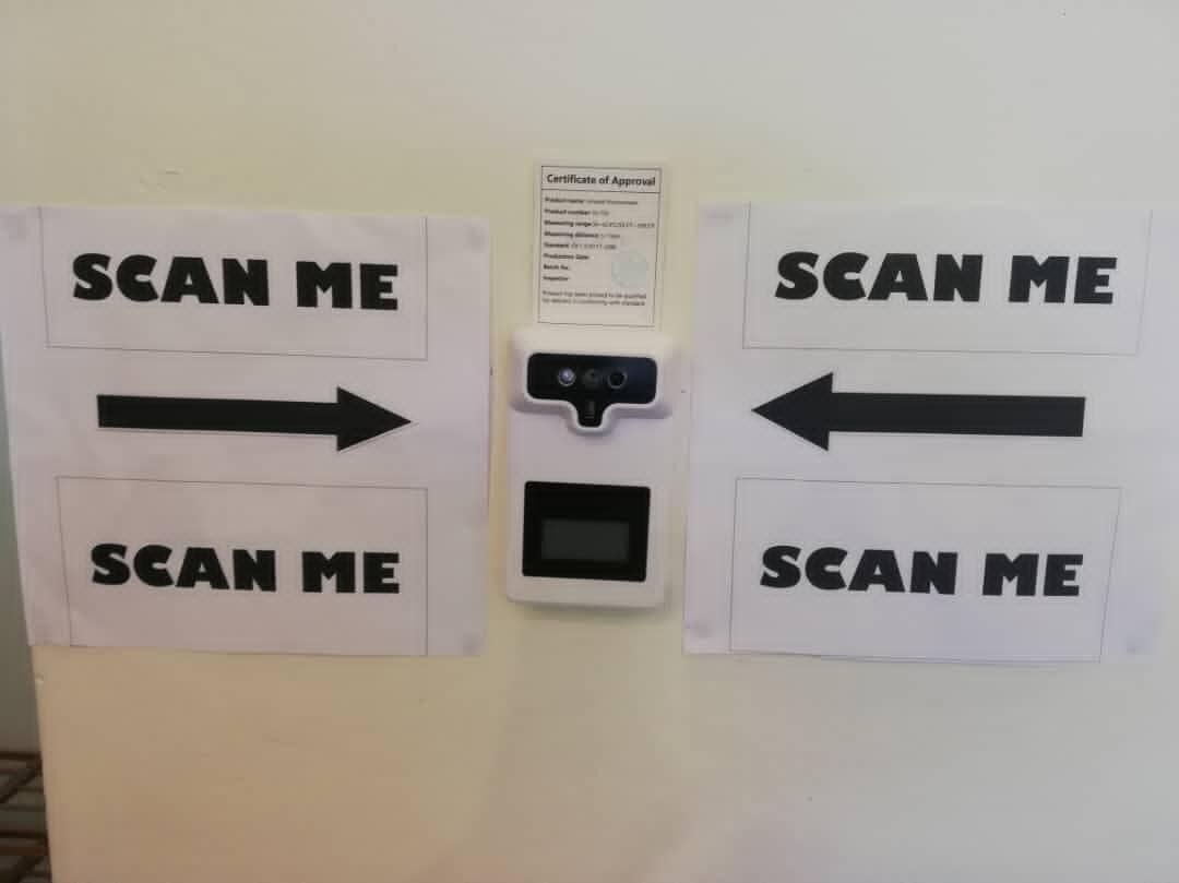 Un mur avec quatre panneaux indiquant « SCANEZ-MOI » et deux flèches pointant vers un scanner.