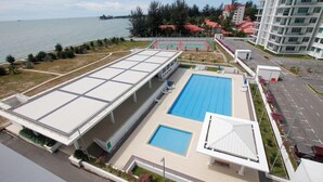 A modern hotel with a large swimming pool, a covered area, and a view of the sea. - Imperial Suites Miri @ Diamond Tower (Miri)