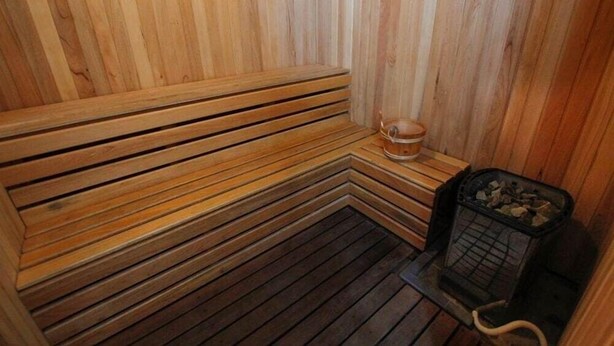 A wooden sauna with benches and a small table with a cup. - Imperial Suites Miri @ Diamond Tower (Miri)