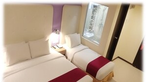 A hotel room with two beds, a window, and a door. - Lumut Suites (Lumut)