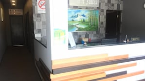 A reception desk with a sign for 'Imut Suites,' a no-smoking sign, and directional signs for rooms 100-114 and the restaurant. - Lumut Suites (Lumut)