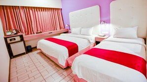 A hotel room with two beds, a nightstand, a small desk, and a window with curtains. - Lumut Suites (Lumut)
