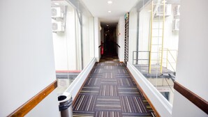 A hotel corridor with a patterned carpet, glass railings, and air conditioning units. - Lumut Suites (Lumut)