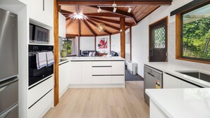 A modern kitchen with white cabinetry, stainless steel appliances, and a wooden ceiling. - Aquarius home with vintage aesthetic and Lakeview (Rotorua)
