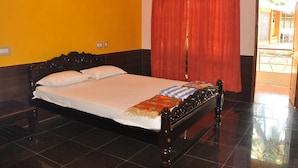 Una habitación con cama, cortina roja y puerta que da al exterior.