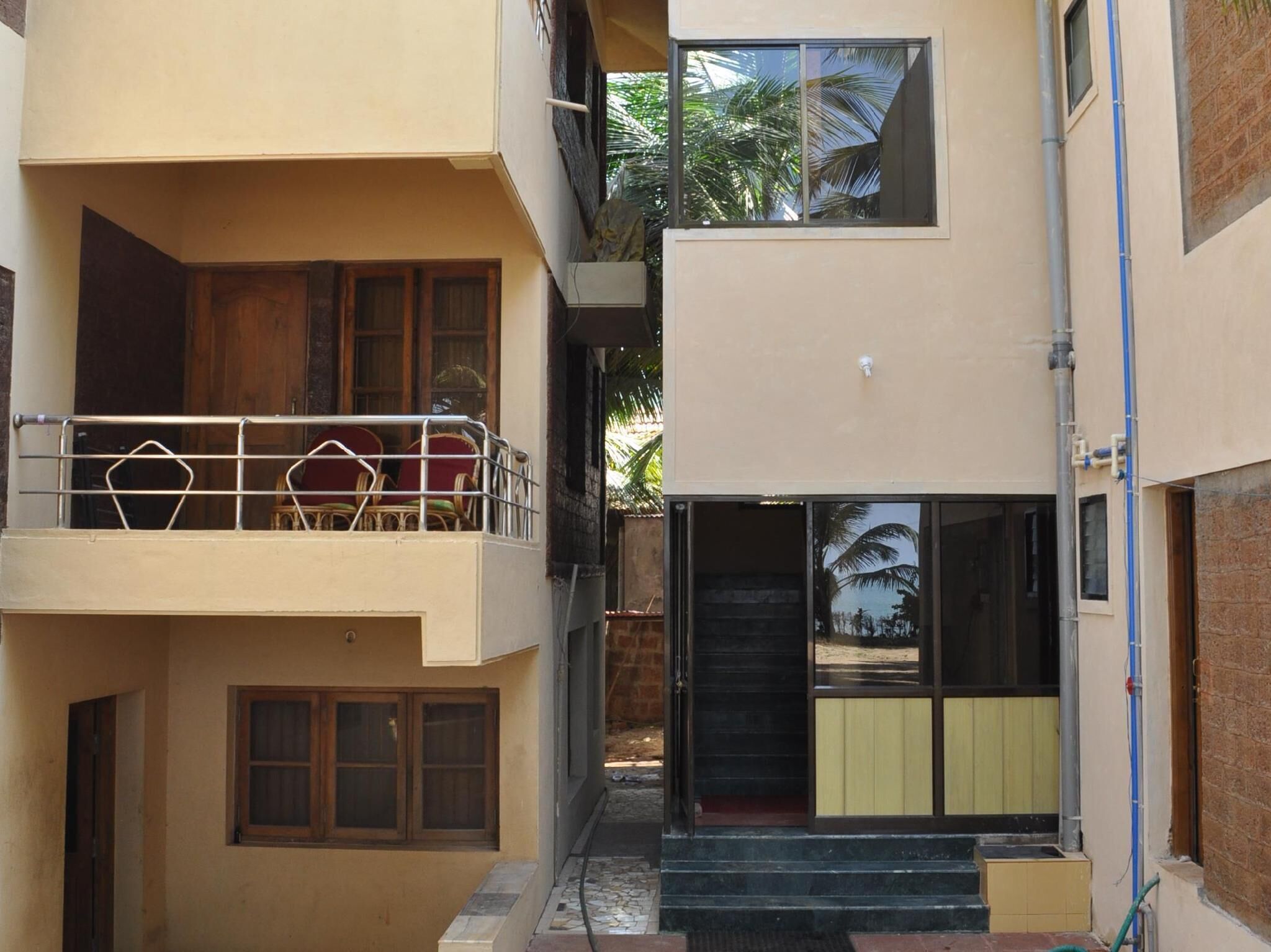 A multi-story building with a balcony on the upper floor, a door with a glass panel, and a small outdoor area with steps leading to the entrance.