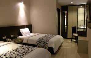 A hotel room with two beds, a desk with a phone, a chair, and a mirror.