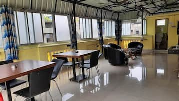 A spacious indoor area with a high ceiling, large windows, and a tiled floor.