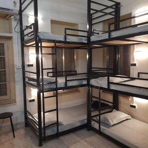 A bunk bed room with a window, a radiator, and a wall-mounted light fixture. - Bubble Beds Hostel (Kolkata)