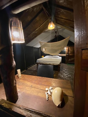 Una camera da pranzo rustica mansardata con un letto, una lampada a sospensione e un tavolo di legno con diversi oggetti.