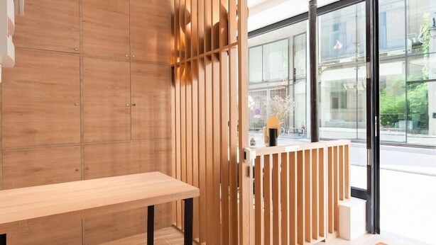 Un intérieur moderne avec un séparateur en bois, un banc et une vue dégagée grâce à de grandes fenêtres.