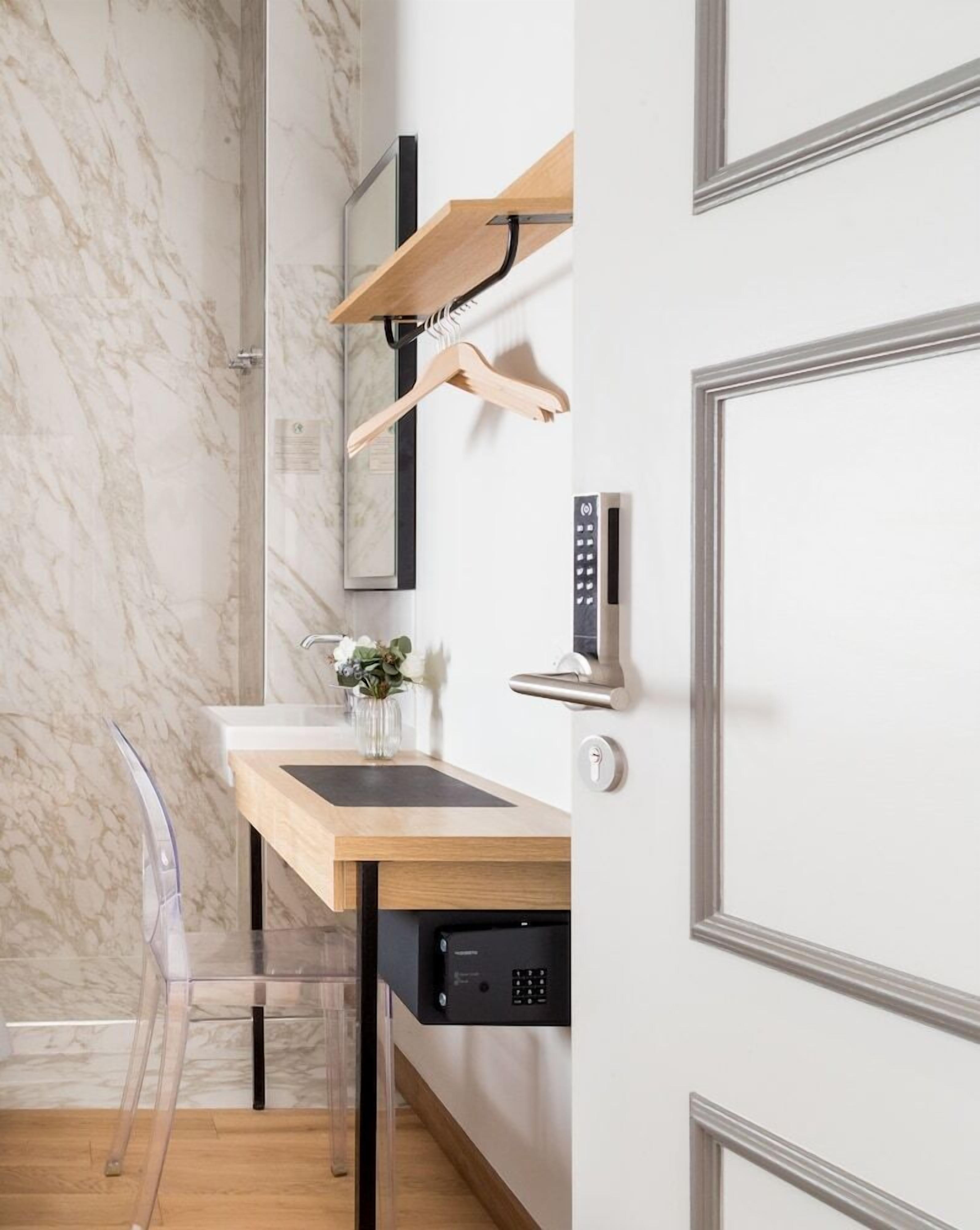 A bathroom with a marble wall, a wooden vanity with a sink, a mirror, a towel rack, a shower, and a built-in dishwasher.