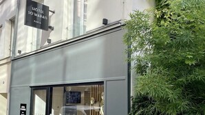 L’entrée d’un hôtel, avec une porte en verre, une enseigne au-dessus de la porte et une petite plante sur la droite.