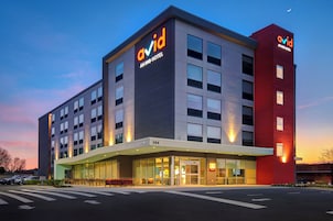 Un hotel moderno con un llamativo letrero 'avid', entrada de vidrio y una pared de acento roja.