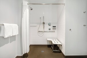 A modern bathroom with a shower, a towel rack, and a small table.