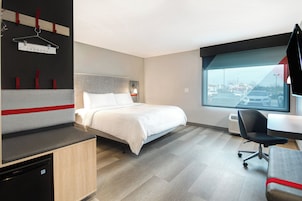 Una habitación de hotel moderna con cama, escritorio y vista a un estacionamiento.