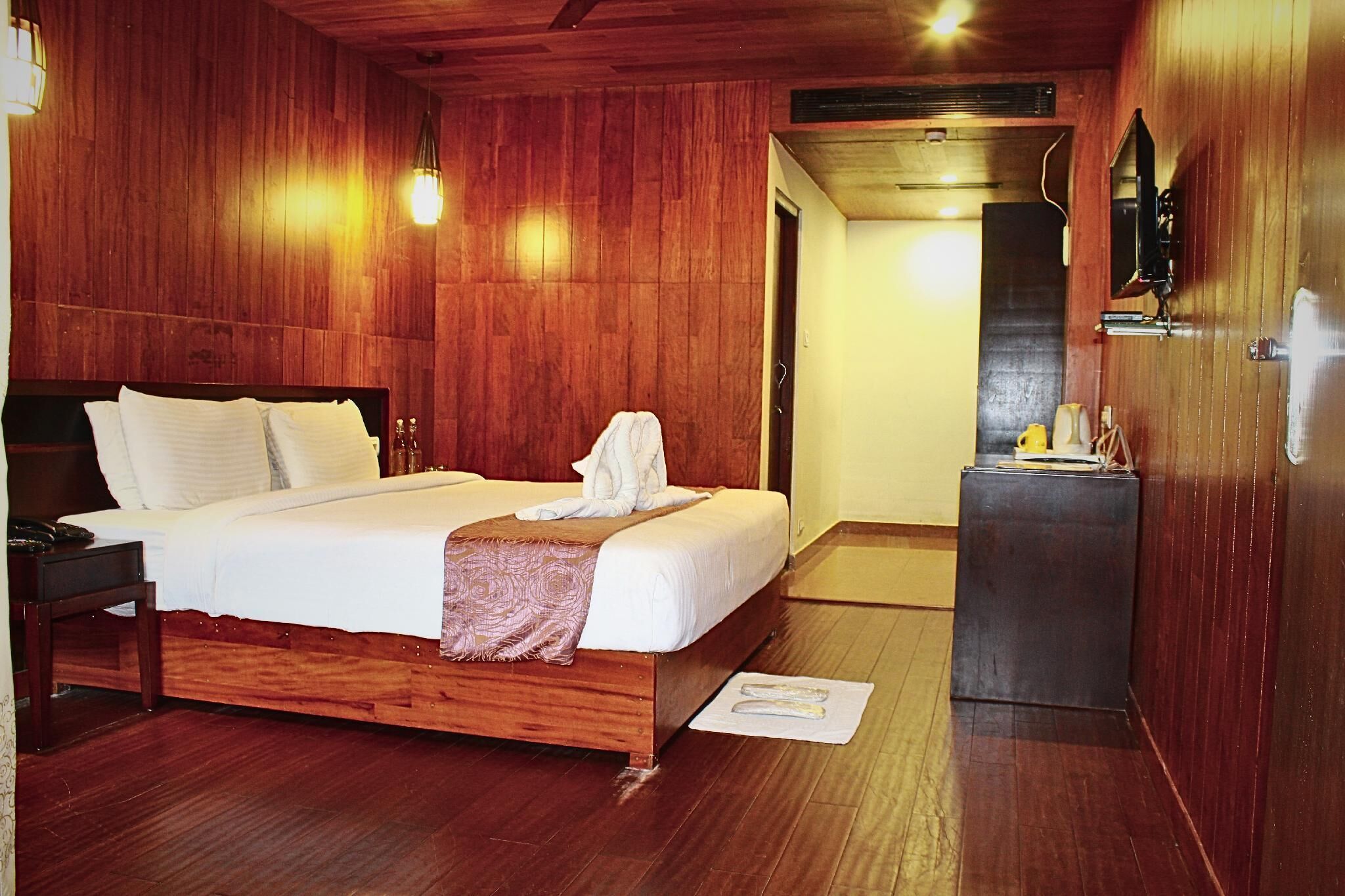 A wooden-paneled bedroom with a bed, bedside table, and a mirror on the wall.