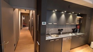 A modern kitchen with a built-in dishwasher, stainless steel appliances, and a wooden floor. - Amosa Hotel Liege & Sava Natures Cuisine (Liege)