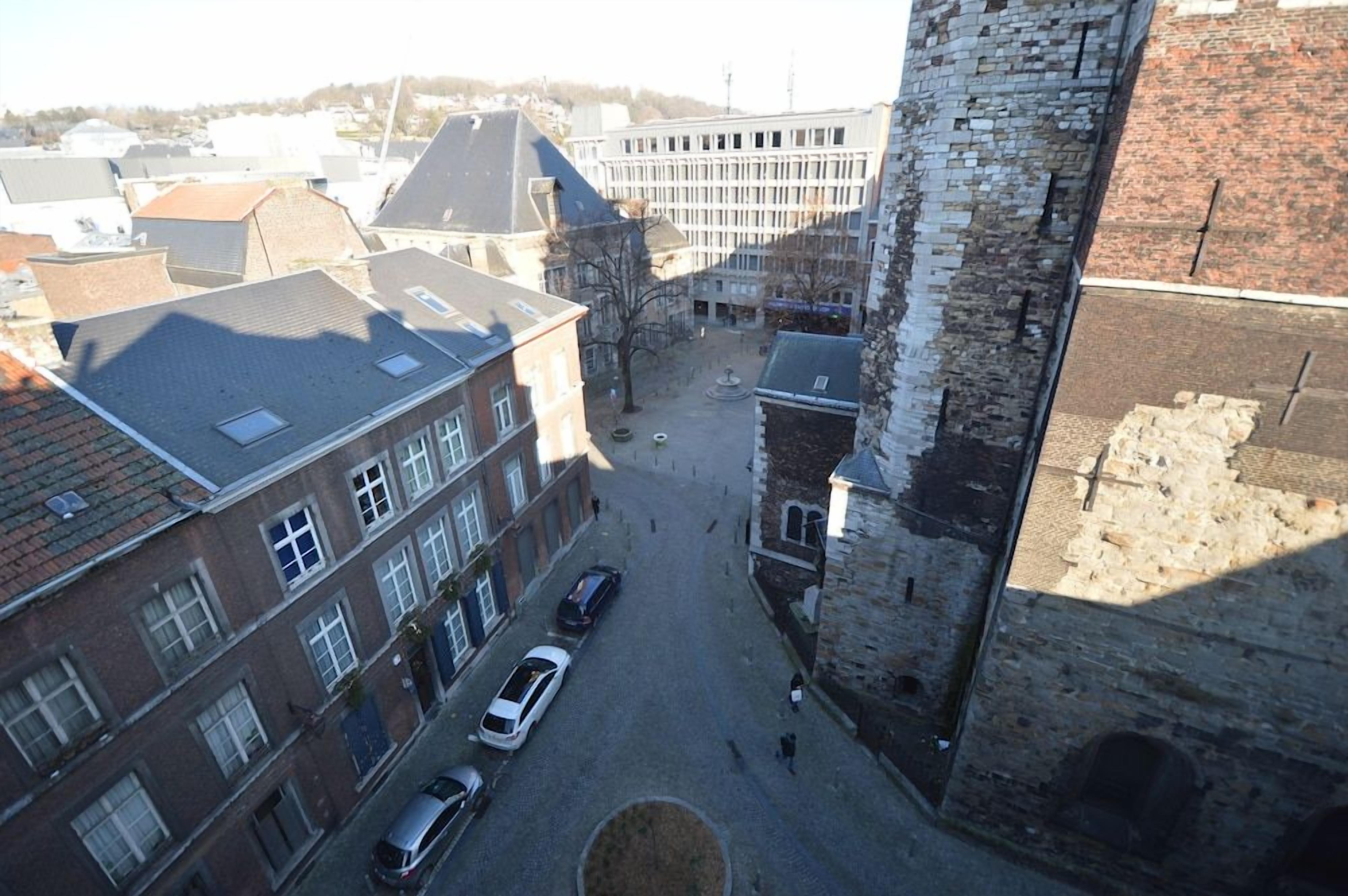 Une cour avec une fontaine, entourée de bâtiments historiques et d’une tour en pierre.