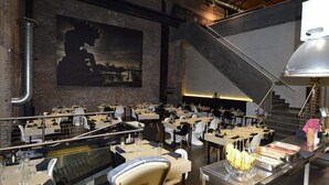 A restaurant with multiple dining tables and chairs, a large painting on the wall, and a staircase leading to an upper level. - Amosa Hotel Liege & Sava Natures Cuisine (Liege)