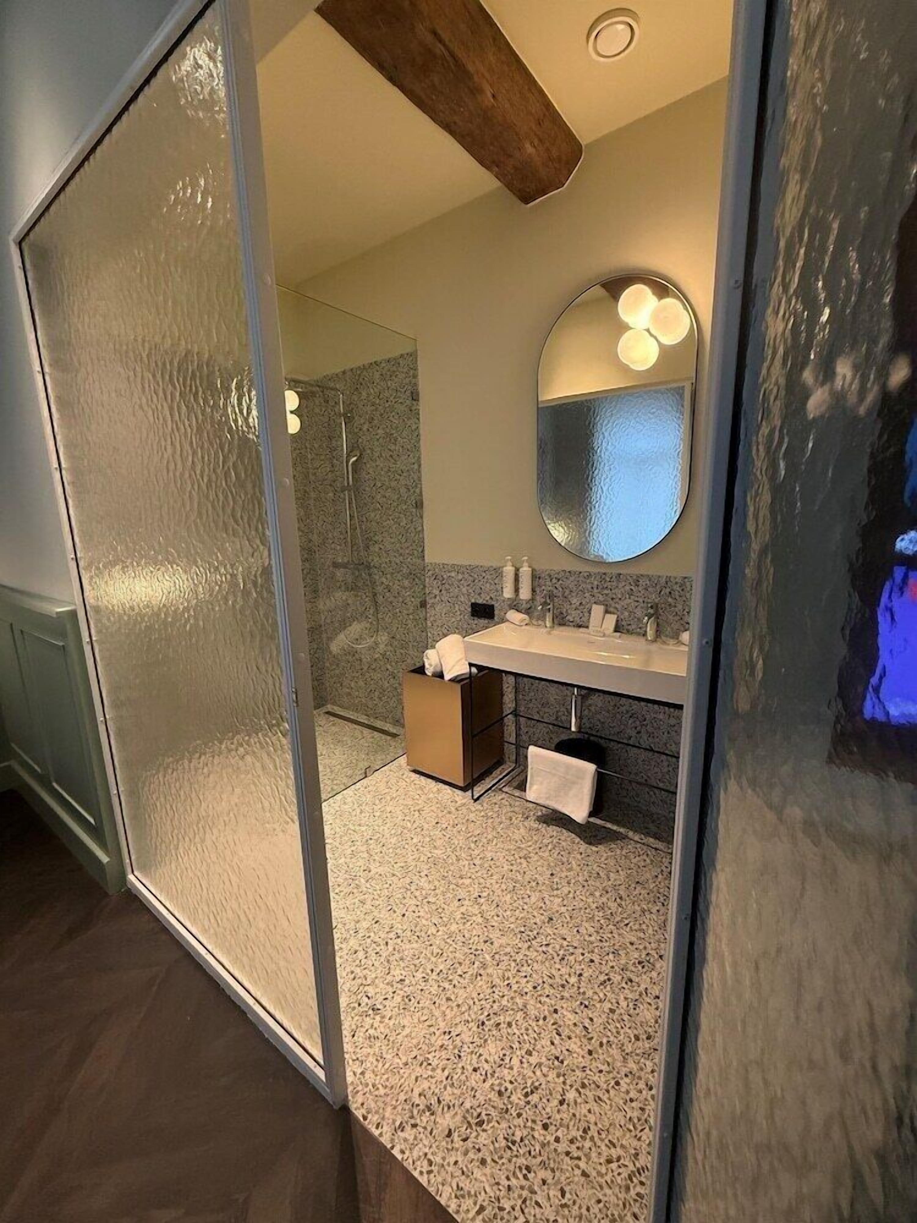 Une salle de bain moderne avec une douche à parois de verre, un meuble-lavabo avec un miroir et un porte-serviettes.