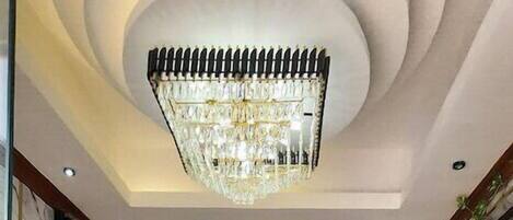 Um hall de hotel com um lustre imponente, paredes de mármore e um padrão decorativo no chão.