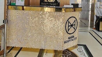 A reception area with a tiled counter, a logo, and a sign indicating a 2m safe distance.