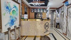 Zona de recepción con piso de mármol, mostrador de recepción y una pared con retratos enmarcados.