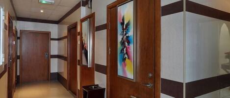 A hotel corridor with wooden doors, a bench, and a sign.