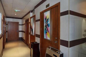 A hotel corridor with wooden doors, a bench, and a sign.