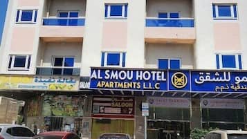 A multi-story hotel with balconies, a sign for Al Smou Hotel, and valet parking.