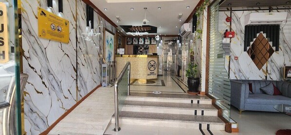 A hotel lobby with marble walls, a reception desk, a staircase, and a seating area. - Al Smou Hotel Apartments - Maha Hospitality Group (Ajman)