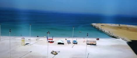 A beach with tents, a lifeguard tower, and a pier.
