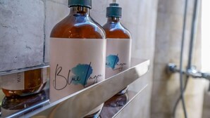 Two bottles of Blue Lagoon soap on a metal shelf in a bathroom. - Blue Lagoon Avia Villas (Ceningan Island)