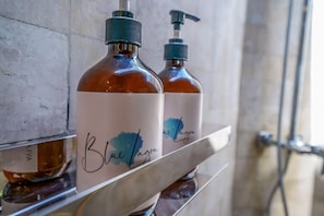 Zwei Flaschen Blue Lagoon Seife auf einem Metallregal in einem Badezimmer.