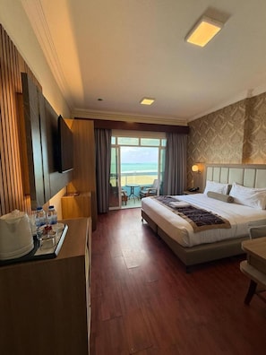 Ein Hotelzimmer mit Bett, Schreibtisch mit Flachbildfernseher, Esstisch und Blick auf den Ozean.