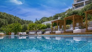 A swimming pool with clear blue water, wooden pergolas, and lounge chairs. - Ionian Eye (Corfu)