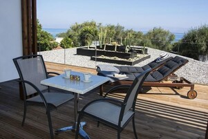 Un balcón con mesa y sillas, una tumbona y un jardín de cactus.