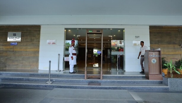 A hotel entrance with a security guard, a valet desk, and a sign indicating the entrance.
