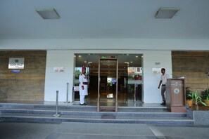A hotel entrance with a security guard, a valet desk, and a sign indicating the entrance.