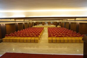 A large conference room with rows of yellow chairs and tables, a polished floor, and a high ceiling. - Minerva Grand Nellore (Nellore)