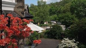 Une maison avec une façade en pierre et un jardin agrémenté de fleurs rouges.