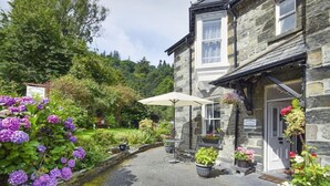Un bâtiment en pierre avec un chemin de jardin, des sièges extérieurs et des jardinières.