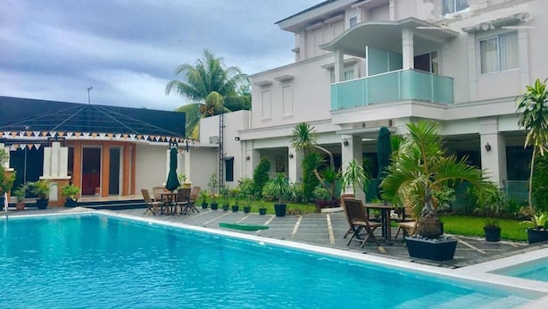 A swimming pool with a building in the background. - Kawana Hotel (Padang)