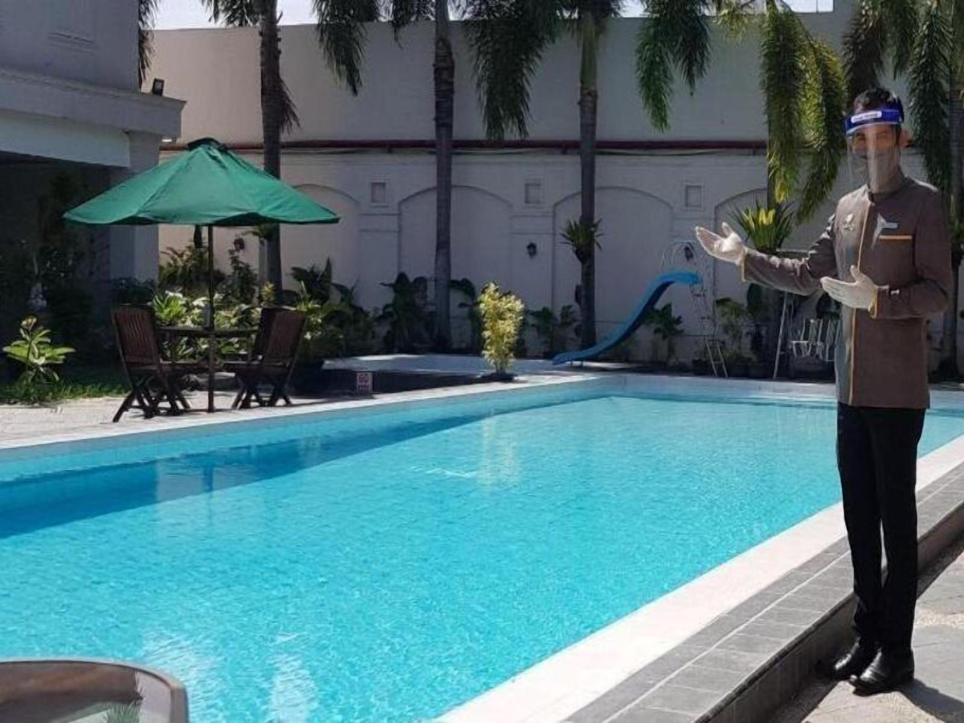 A pool area with a lifeguard, lounge chairs, and a slide.